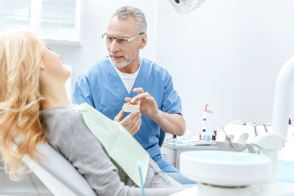 dentysta pokazuje model szczeki pacjentce w klinice stomatologicznej